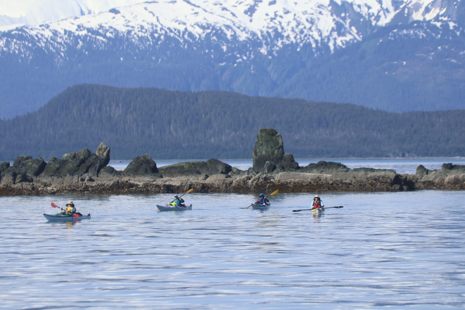 Sea kayakers in front of snow-capped Alaska mountains