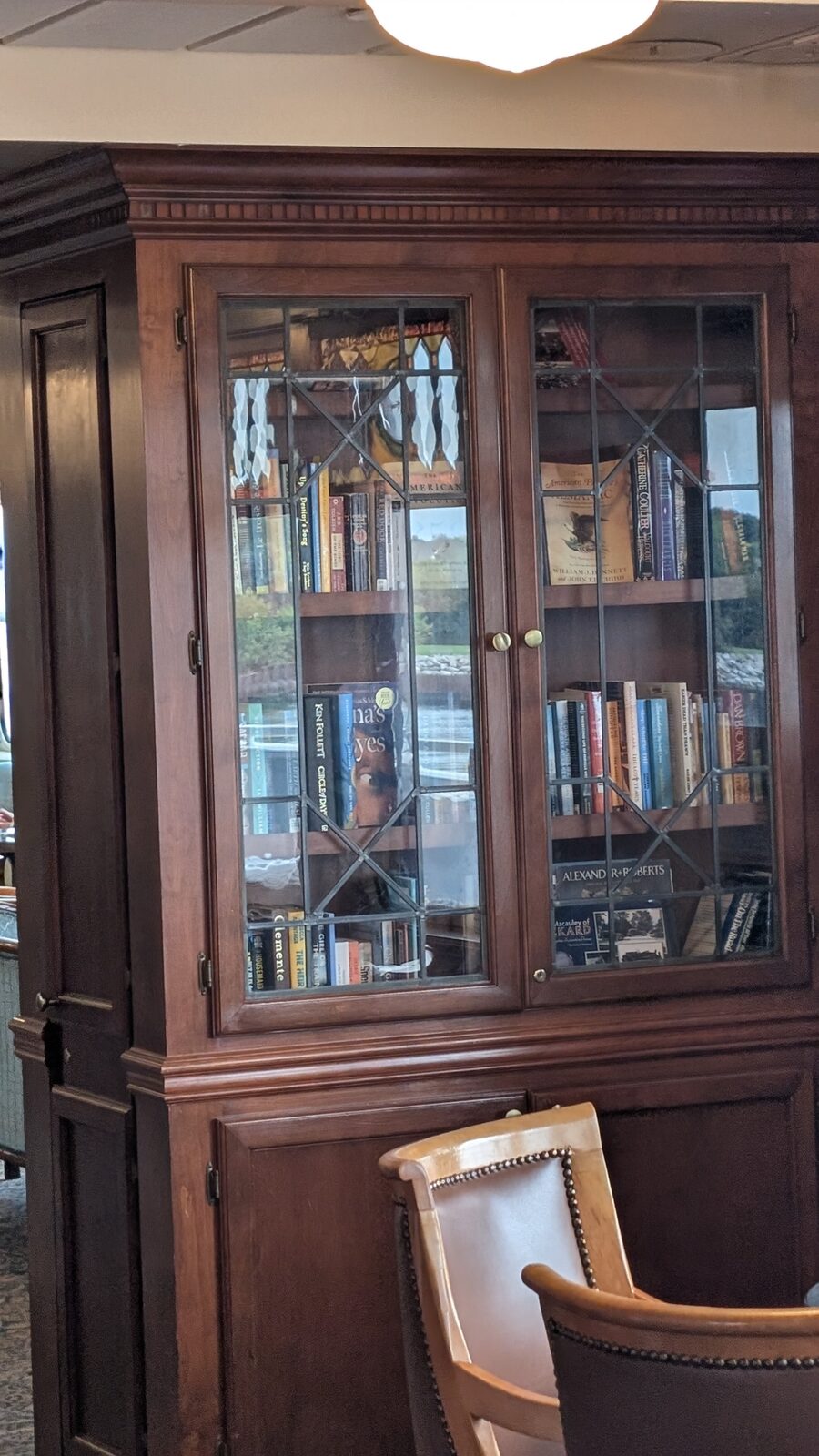 Glass-front wooden bookcase filled with books in a Victory II lounge