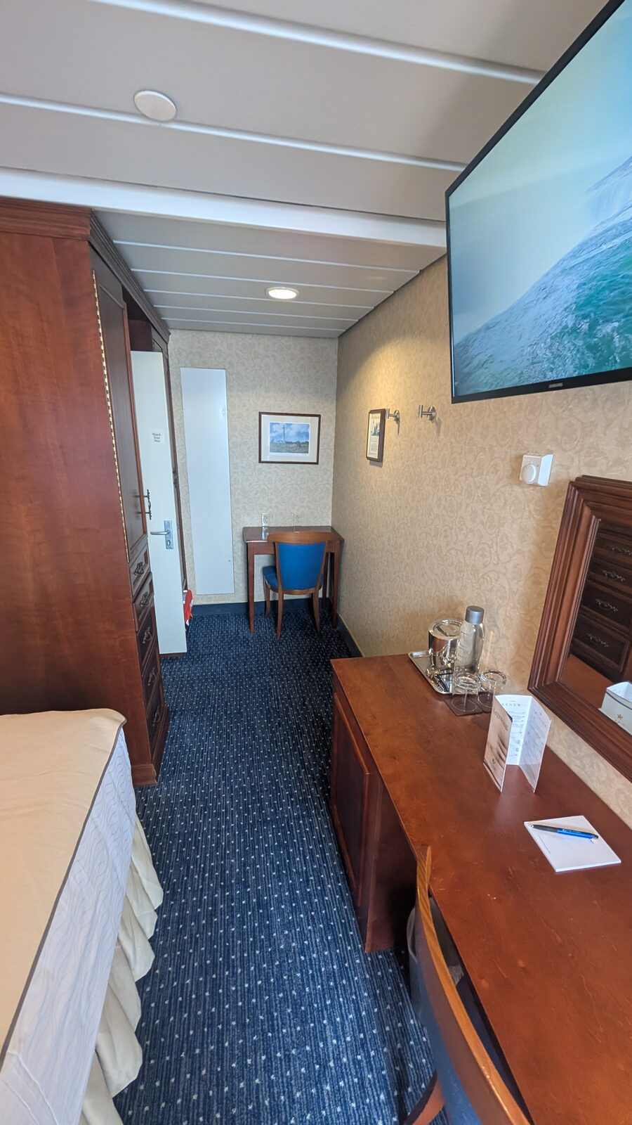 Long view of a Victory II stateroom showing the desk, wall TV, and wardrobe