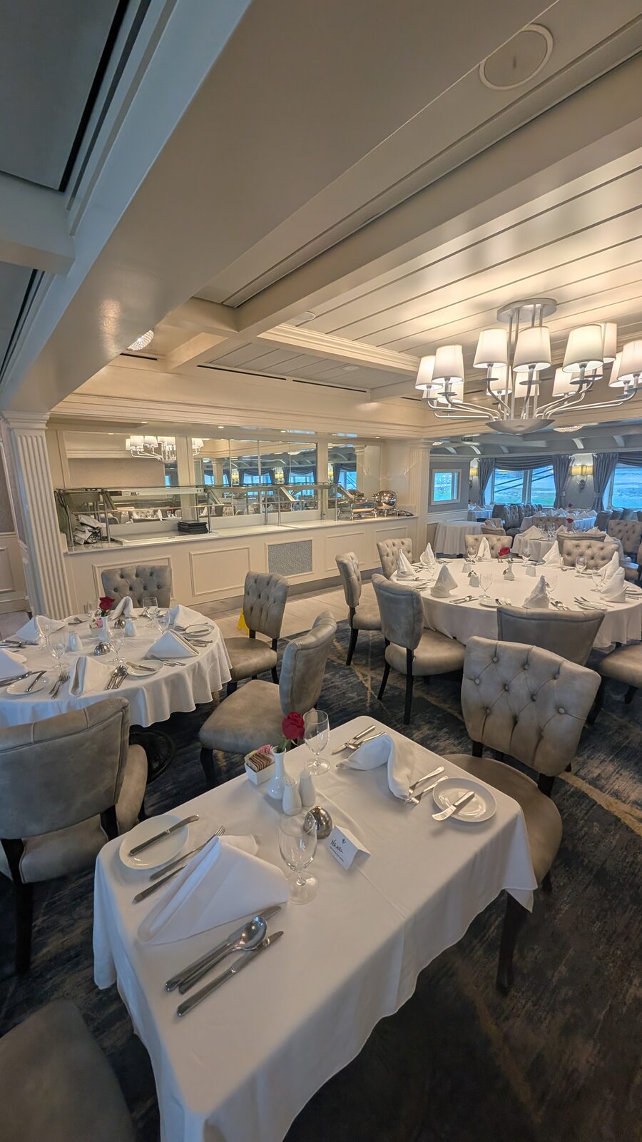 The Coastal Dining Room on Victory II with white tablecloths and chandeliers